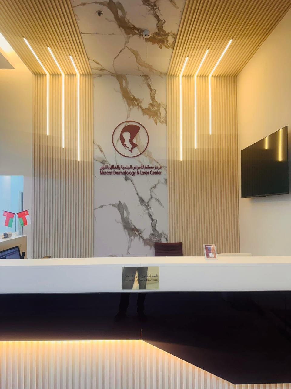 Muscat Dermatology Azaiba clinic reception with marble accent wall and logo